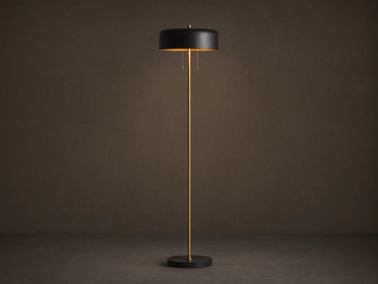 Oliver Floor Lamp: upright brass stem, black cylindrical shade with warm downward glow, black circular base on wooden floor.