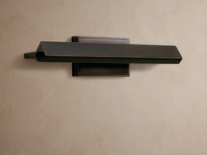Zaeden Picture Light, dark bronze-plated with a horizontal angled bar and rectangular backplate, mounted on a textured brown wall.