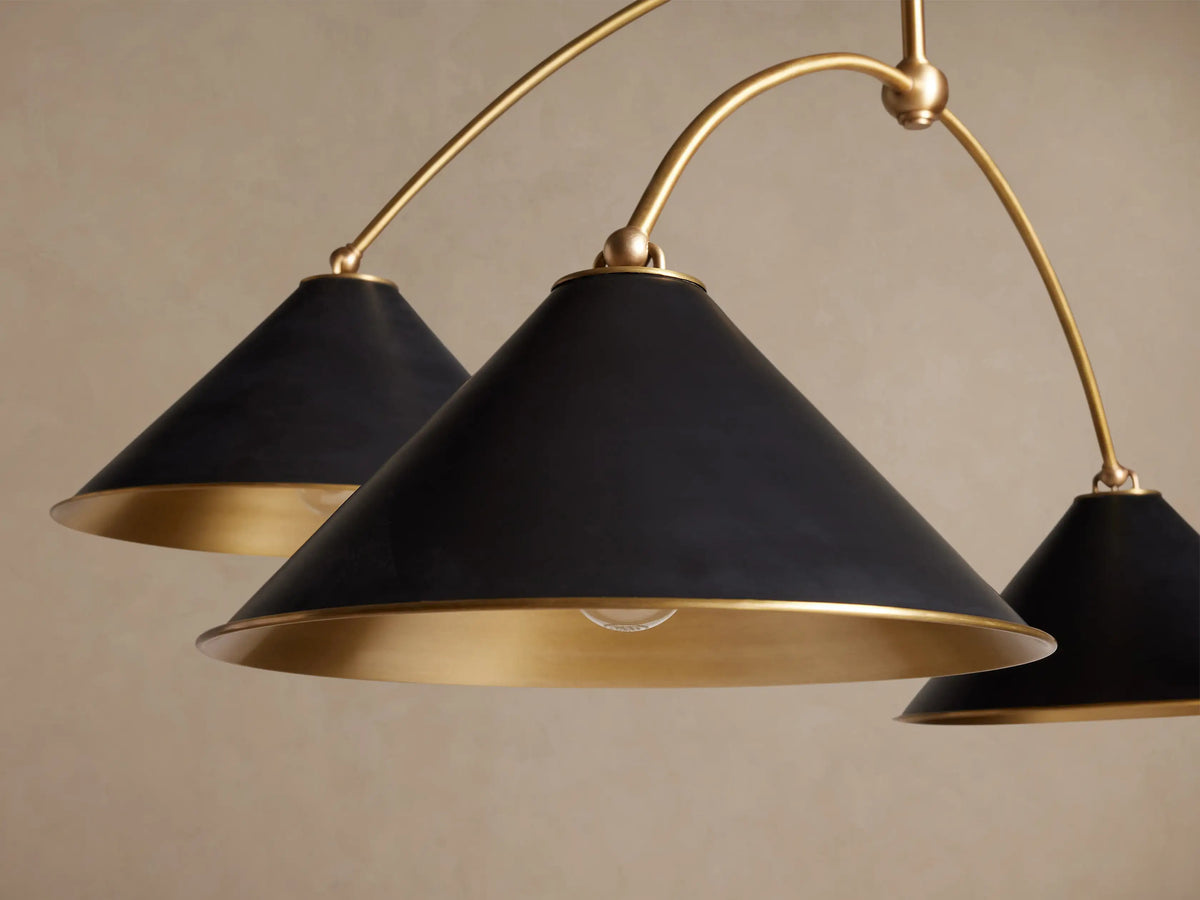 Arno Round Chandelier with four matte black conical shades, polished brass interiors, suspended from curved brass arms.