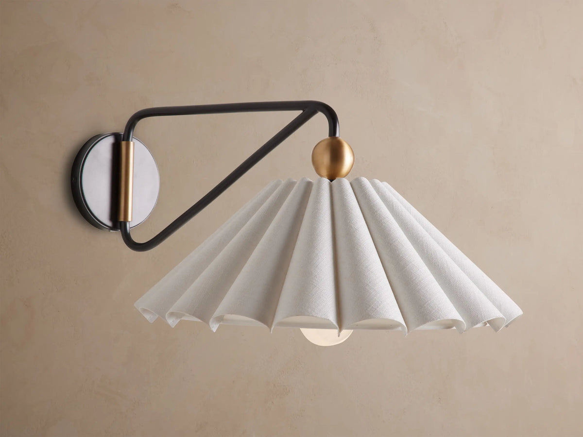 Illuminated Haylen Sconce: black metal arm, circular backplate with antique brass, pleated cream fabric shade.
