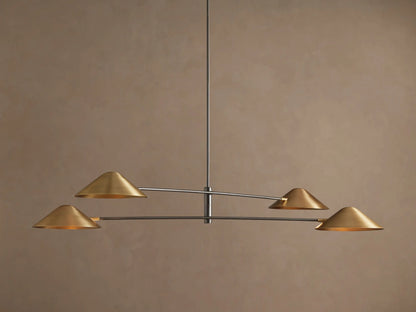 Simms Chandelier with four conical polished brass shades facing down, mounted on dark horizontal arms against a brown wall.