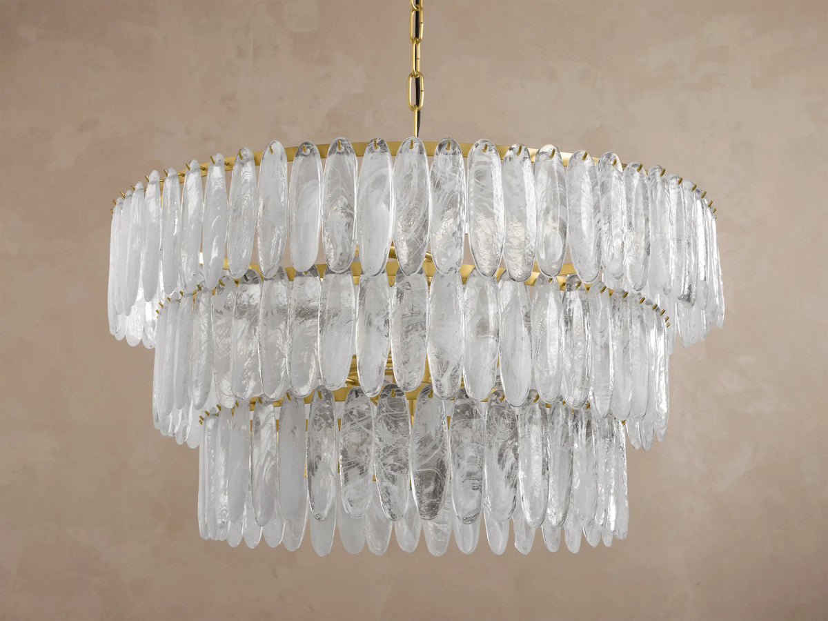 Close-up of a circular brass chandelier featuring numerous hanging clear textured glass panels, illuminated from within.