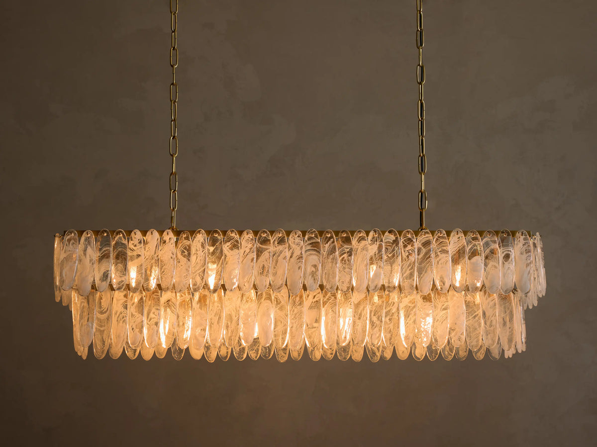Gold rectangular chandelier, two tiers of illuminated clear oval glass with frosted swirls, suspended by chains.