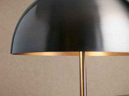 Malcom Table Lamp with a dark pewter dome shade, slender stand, and round base, sitting on a rustic wooden table.