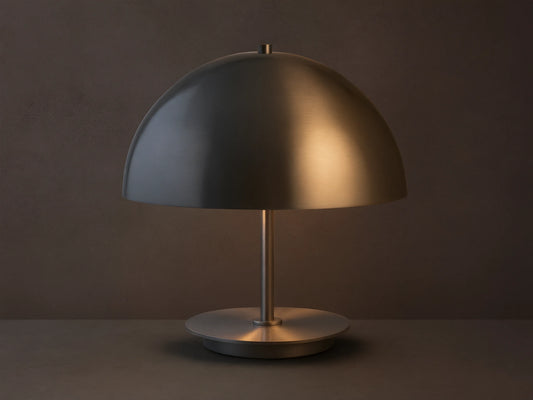 Malcom Table Lamp: dark brushed pewter dome shade, thin stem, and round base on a rustic wooden table.