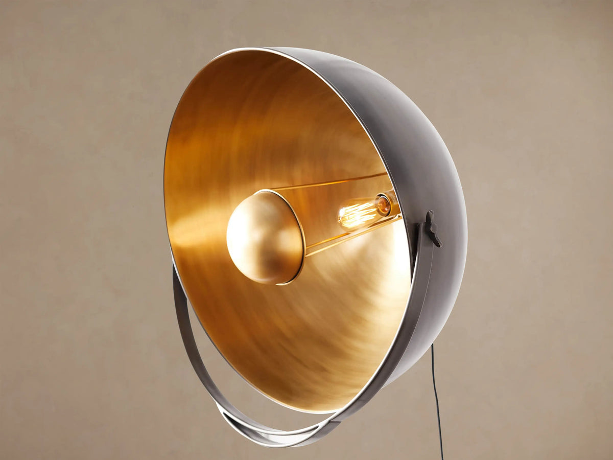 Close-up of a Retro Tripod Floor Lamp's antique brass and black metal base with a knurled knob and tripod legs.