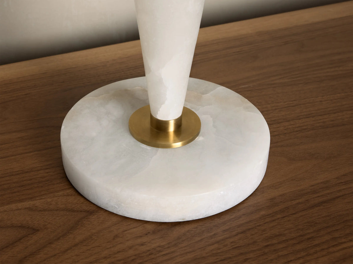 Close-up of the round white onyx lamp base with a golden brass connector, sitting on a wooden surface.