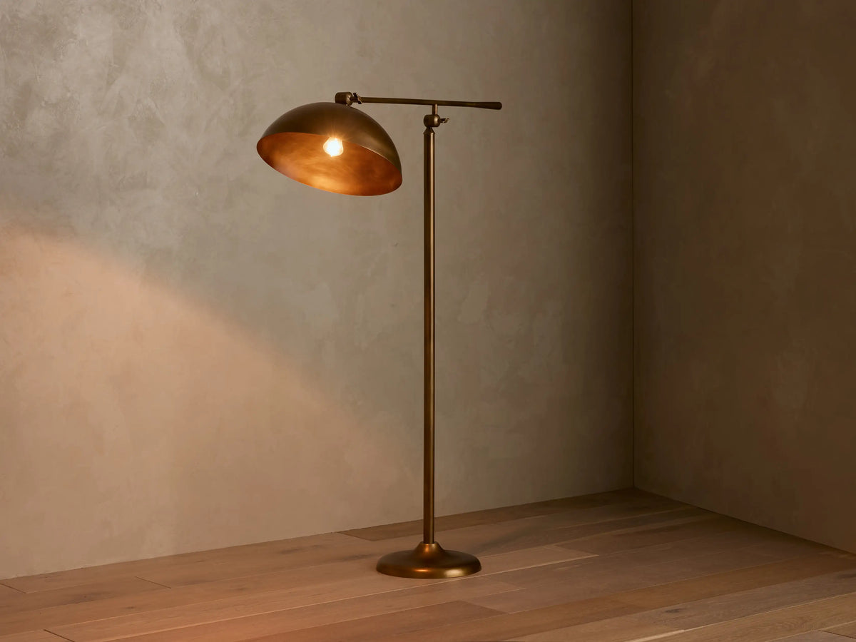 Close-up of the Adjustable Bronze Dome Lamp, featuring its curved bronze shade with a warm glow inside and articulating arm.