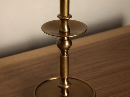 Close-up of the antique brass Winslow Candlestick Table Lamp, showing its textured stem, spherical accent, and upper flat disc.