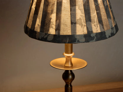 Front view of the lit Winslow Accent Table Lamp, featuring an antique brass finish base and a pleated dark floral fabric shade.