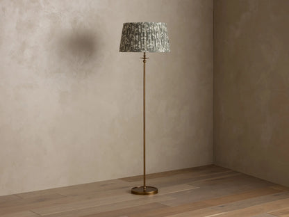 Front view of the Winslow Floor Lamp with an antique brass finish and a pleated muted green patterned fabric shade.