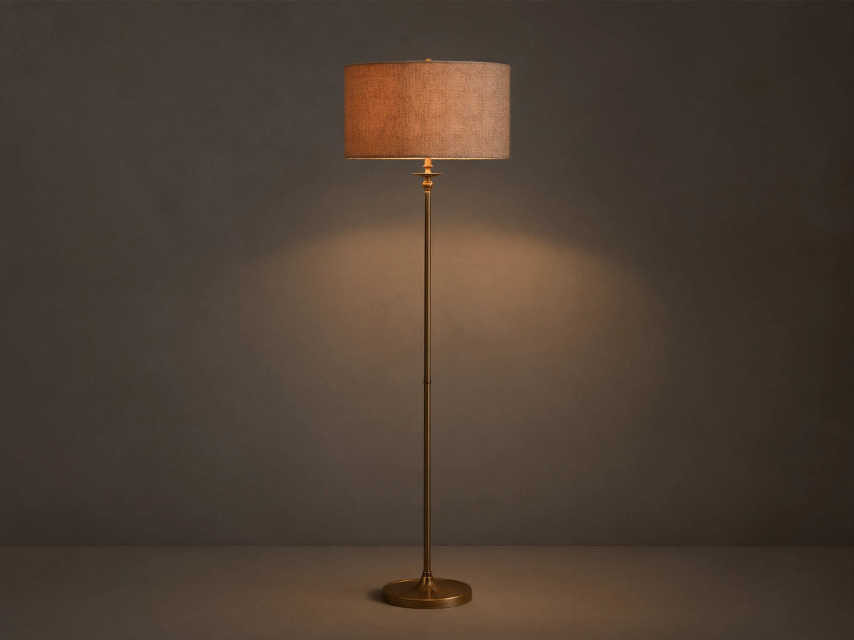 Full view of the Winslow Floor Lamp with antique brass finish and a textured light brown fabric shade, illuminating a room corner.