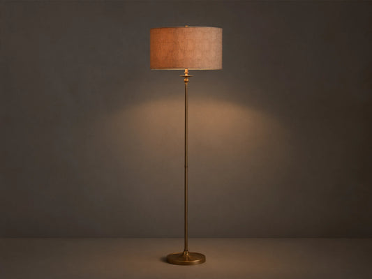 Full view of the Winslow Floor Lamp with antique brass finish and a textured light brown fabric shade, illuminating a room corner.