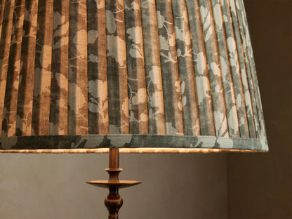 Close-up of the Winslow Floor Lamp, featuring a pleated grey-green fabric shade with white floral pattern, and an antique bronze base.