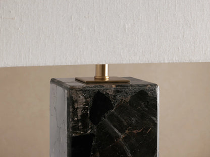 Oren Table Lamp close-up: dark, marbled stone cubic base, brass connector, and textured white linen shade.