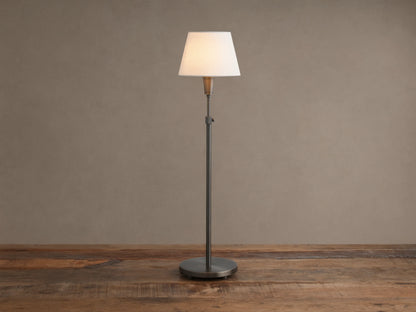 Upright pewter Candice Table Lamp with a creamy white conical shade, standing on a distressed wooden table against a warm neutral wall.