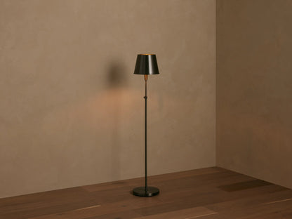 Close-up of Candice Floor Lamp, showing its dark, conical metal shade & brass-toned stem against a warm, neutral wall.