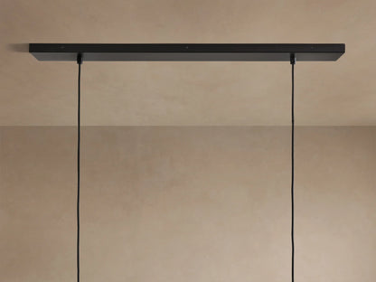 Lena Linear Chandelier close-up: dark, textured alder wood, glowing ochre interior, and reflective mirrored glass panel.