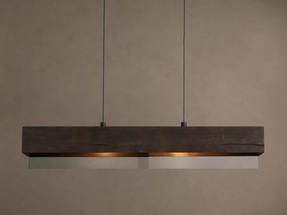 Lena Linear Chandelier: A rectangular dark wood beam with textured grain, featuring mirrored glass below, emitting a warm glow, suspended by black cords.