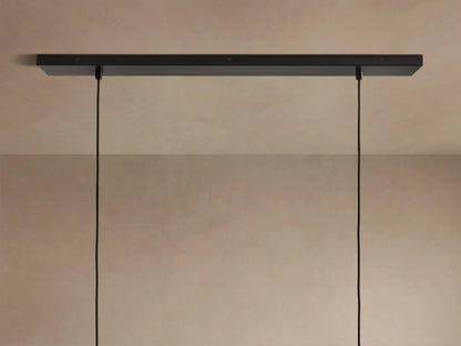 Close-up of Lena Linear Chandelier: dark textured alder wood top, ochre-finished interior, and mirrored glass panel.