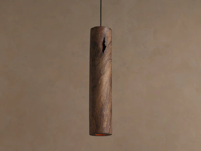 Dedalo Pendant: Rustic dark brown cylindrical wood pendant with natural knots & grain, hanging vertically on a beige wall.