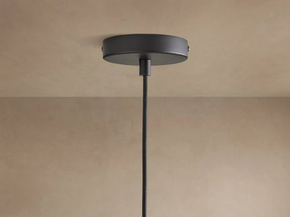 Dedalo Pendant: cylindrical milpa wood light with light ochre finish, natural grain, and a visible crack, hanging from a black cord.