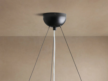Close-up of Arruga Chandelier; a clear, glowing bulb illuminates the dark, textured, irregularly shaped milpa wood dome from below.