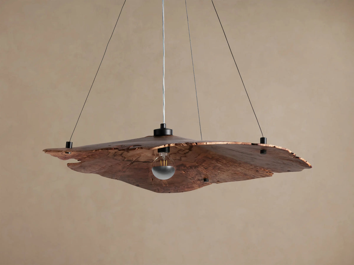 Arruga Chandelier, handcrafted from natural milpa wood with irregular edges, suspending an exposed bulb, against a warm beige background.