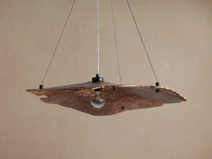 Arruga Chandelier, handcrafted from natural milpa wood with irregular edges, suspending an exposed bulb, against a warm beige background.