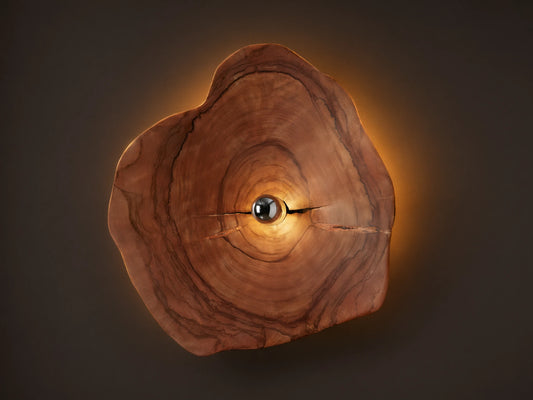 Arruga Sconce: Irregular natural wood slice with visible grain and cracks, light bulb glowing warmly in the center, mounted on a neutral wall.