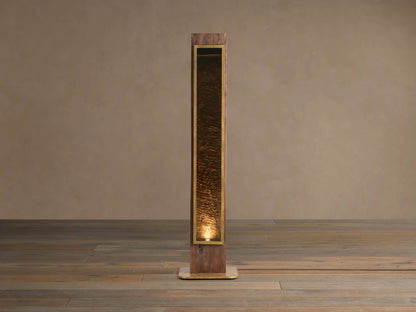 Vigas Floor Lamp: Tall wooden lamp with brass trim, illuminated mirrored glass revealing a textured interior, standing on wood floor.