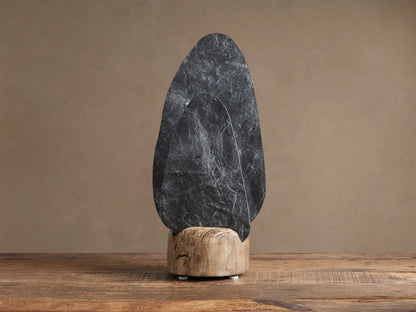 Shinto Table Lamp. Two irregular slate stone shades, dark gray front, lighter illuminated rear, in a natural wood base on a wood table.