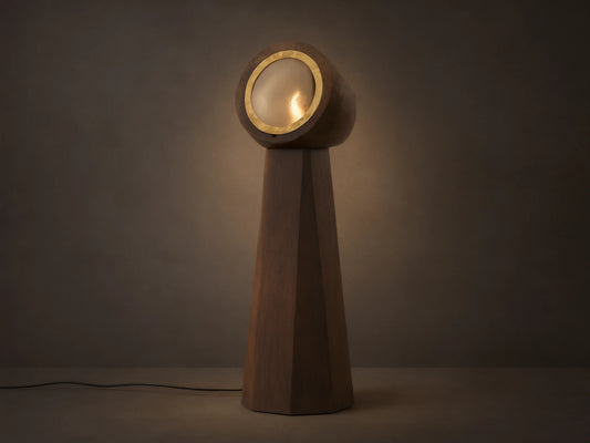 Agustin Floor Lamp: Dark wood faceted base with a round, gold-rimmed opaque glass light fixture, glowing warmly.
