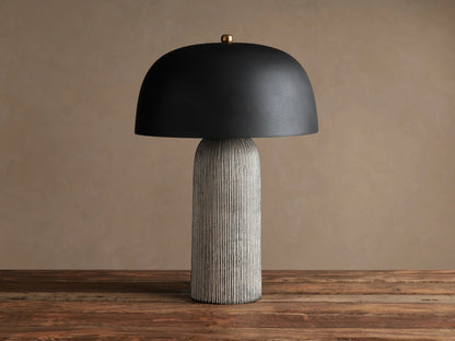 Ira Striped Table Lamp with black dome shade, light-colored vertically ribbed base, on wood table, softly lit.