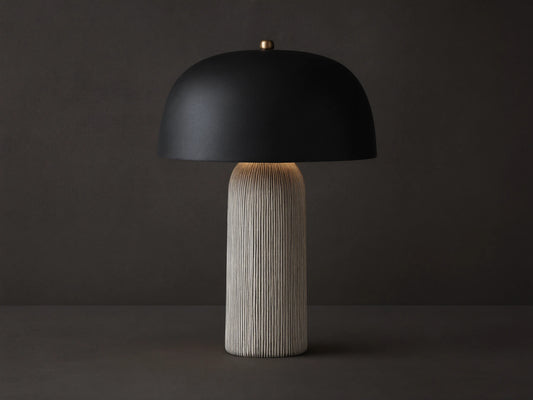 Ira Striped Table Lamp with black dome shade, light-colored vertically ribbed base, on wood table, softly lit.