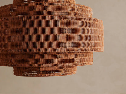 Paloma Chandelier: Tiered handwoven warm brown rattan shade, suspended from a metal chain against a neutral background.