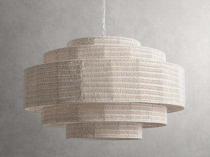 Paloma Chandelier with layered handwoven rattan shade in soft white, suspended from a chain against a gray background.