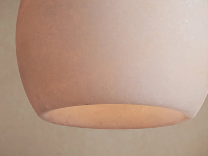 Arica Pendant featuring a white, spherical alabaster shade hanging from a thin cable against a neutral beige background.