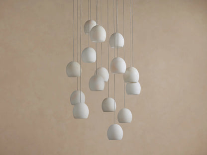 Arica Round Chandelier: Multiple round, illuminated alabaster shades hanging at different heights against a warm beige wall.