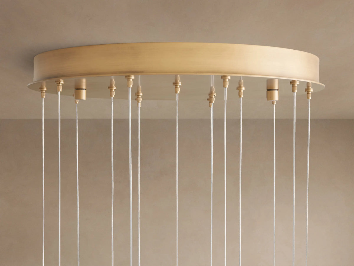 Arica Round Chandelier: Brass circular ceiling mount with numerous white suspension cables hanging vertically.