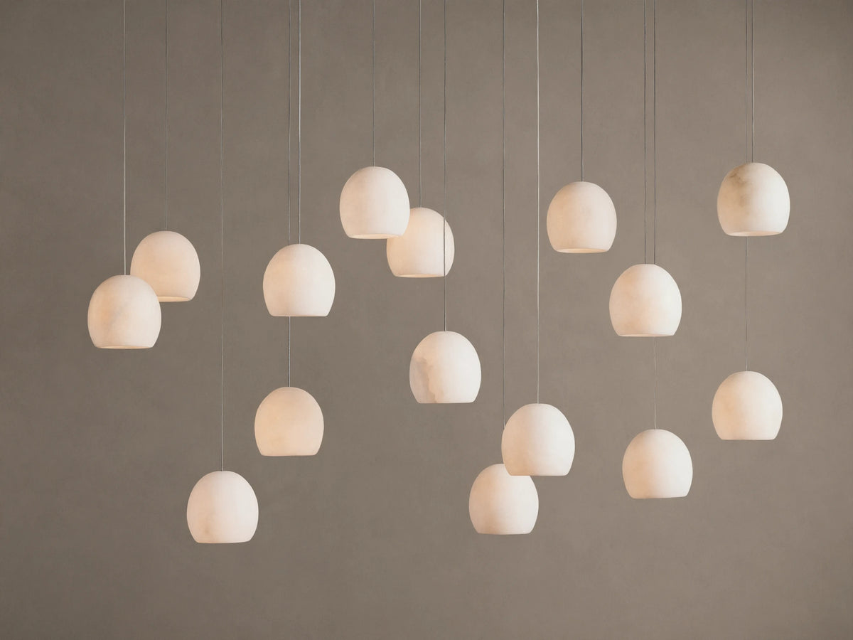 Arica Linear Chandelier with multiple glowing, spherical alabaster shades hanging at varying heights against a warm neutral wall.