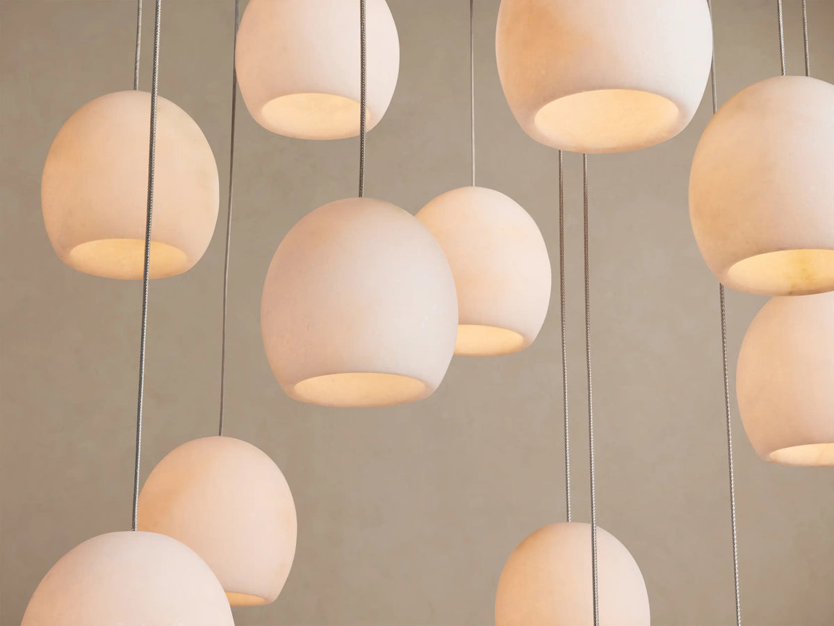 Arica Linear Chandelier featuring multiple off-white, spherical alabaster shades with natural patterns, suspended at varying lengths.