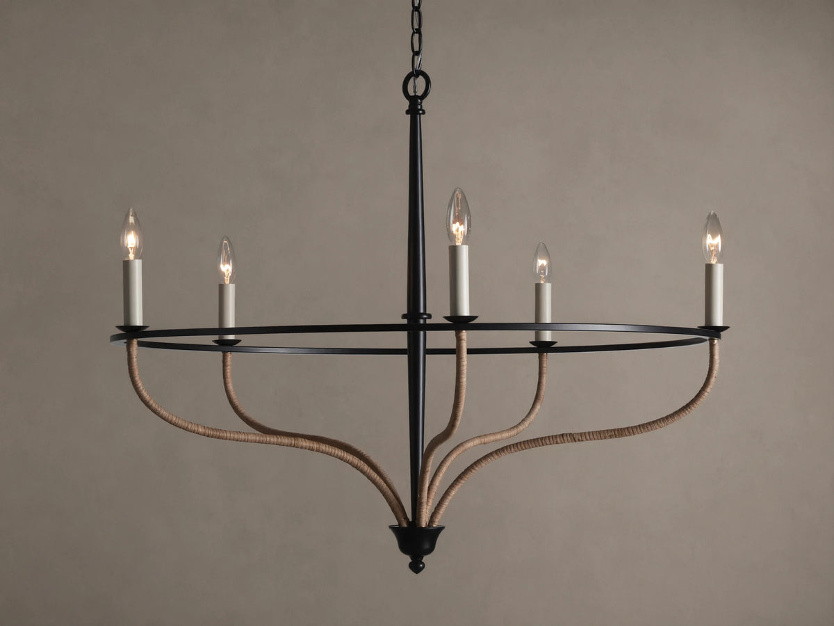Black iron Rosalind chandelier with five illuminated candle-like bulbs. Curved arms are wrapped in natural rattan.