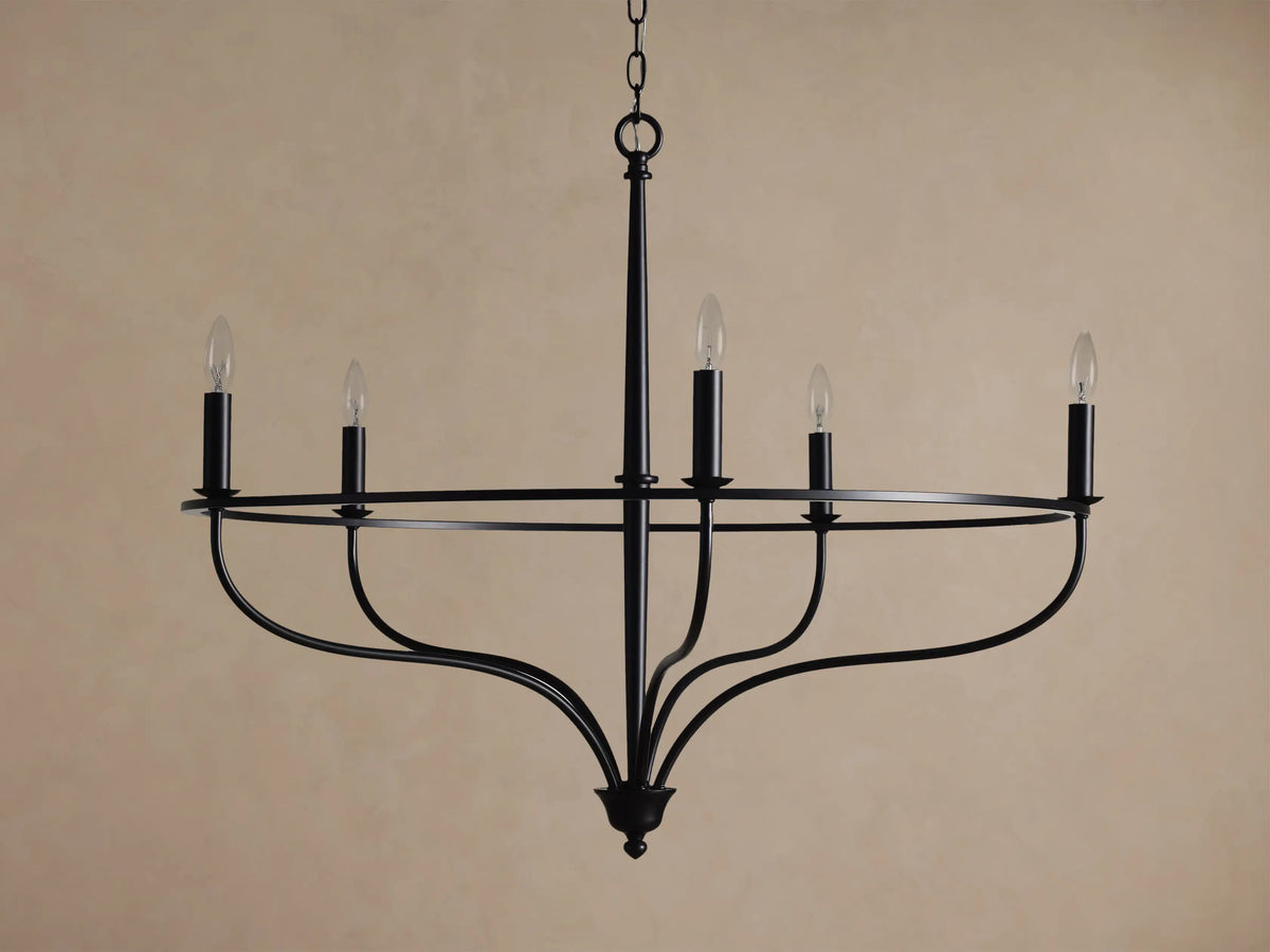 Rosalind Chandelier, matte black, with five lit candelabra bulbs on a circular frame, suspended by a chain.