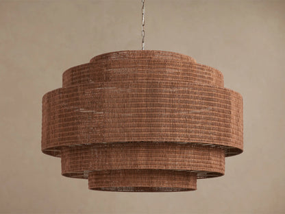 Paloma 52" tiered brown woven rattan chandelier hangs from a chain, with warm light glowing from within its shades.