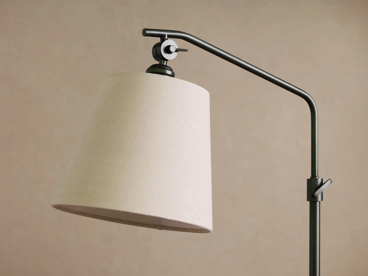 Kellen Floor Lamp, dark oil-rubbed bronze, with an adjustable arm and a tapered beige linen shade, standing on a wood floor.