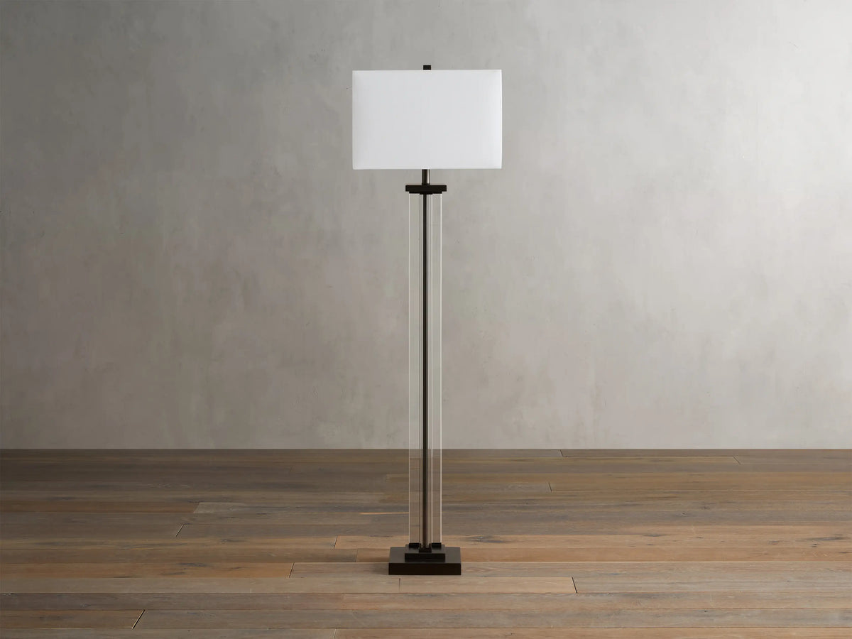 Base of the Dawson Floor Lamp featuring clear crystal columns and a metallic square base on a wooden floor with visible clear cord.