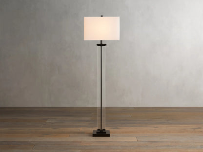 Dawson Floor Lamp with a rectangular white shade, clear crystal and iron base, on a wooden floor against a light wall.
