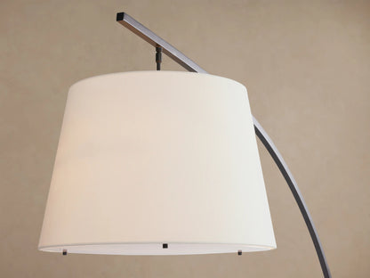 Tadeo Floor Lamp with dark arched stand, white linen shade, and dark espresso marble base, on wood floor.