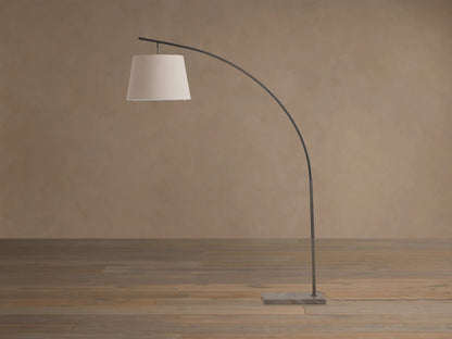 Tadeo Floor Lamp with dark arched iron stand, light linen shade, and rectangular espresso marble base on wood floor.